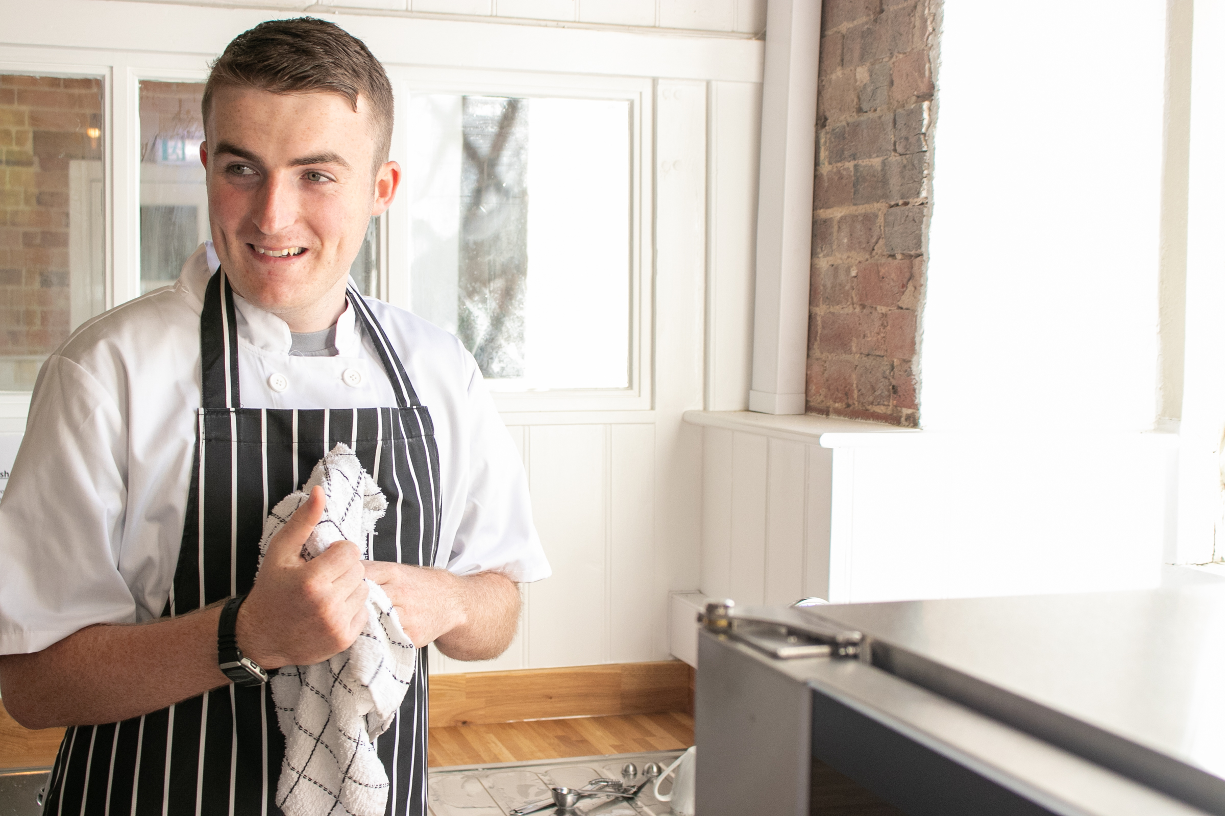 EMA student using a teatowel in the Moreton tearooms kitchen.