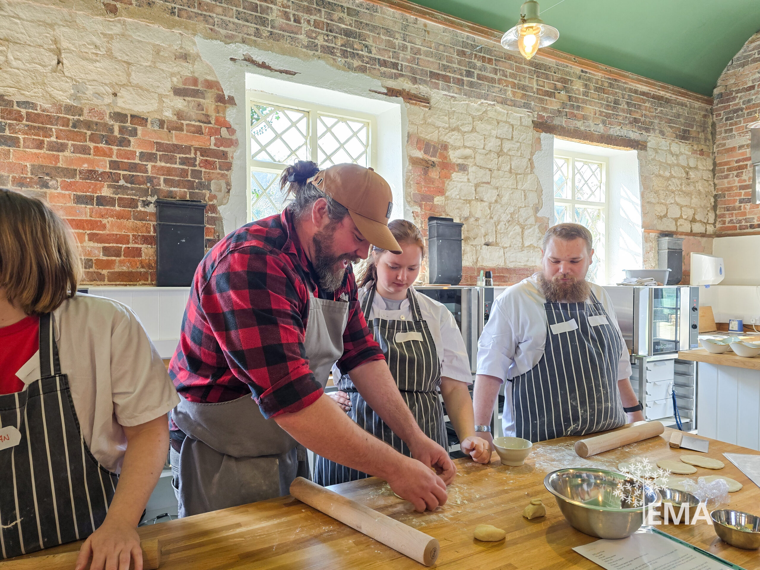 one ema tutor and three ema students making food in the moreton tearooms - rolling out dough and flattening it with a rolling pin